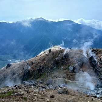 山肌全体から火山の蒸気。その先に浮かぶ霞沢岳。