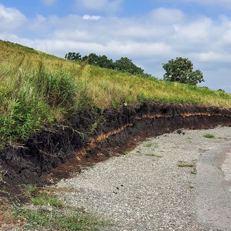 受付のすぐ横の道。手前が公園の入口になる。横の斜面には、特徴的な地層が見て取れる。