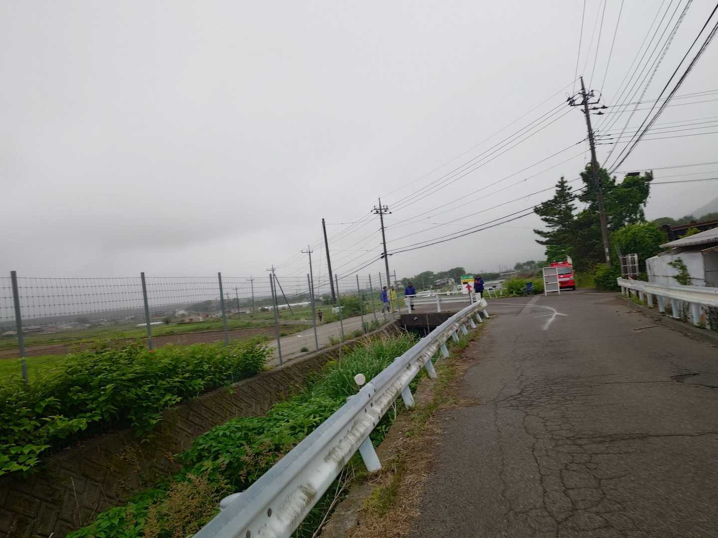 というか、私だけ？？トレランレースでの舗装路走はなんでこんなにツラいのでしょうか？
ぶらぶら歩いたり🚶フラフラ走ったり🏃うわーんと突然泣き出したり😭を繰り返しながら進みます。

農道、長げーんだyo!!
消防団分岐ポイントが見えた！
ここを二周するので、この祝福アイテムのタスキは周回遅れと区別するためなんですね。
消防団が配置されている分岐ポイントではZARDとか大黒摩季とかのオレ達団塊ジュニア世代が喜ぶ音楽がフェス状態レベルの音量でガンガン鳴り響いており、”田園風景の雰囲気が台無し”とか”もうちょっと選曲何とかなんない？”みたいな口コミの書き込みがあったりするのですが、これには理由があります。
ずばり獣対策！
クマは麓が騒がしいとひきこもる習性があるのです。これはタケノコ農家でバイトしていた私も知っています。農家では麓にある集積ポイントの軽トラ基地でラジオ人生お悩み相談を山々に向かって放映しとりました。
さらに人里に降りてくるイノシシは人間を舐めきっているので、走っていると追いかけてくることもあるらしい。ラジオの音はそういう輩が距離をとってくるアイアンドームのような役割があるのだ。
ちなみに、野鳥もこの人工的な音が嫌いで、イヤホンから漏れる音にもストレスを感じるらしい。日本野鳥の会界隈の人がイヤホン勢を嫌厭するのはこういうこと。