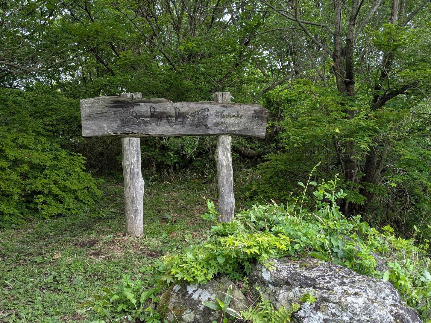 広場の先に山頂標識が立っている
