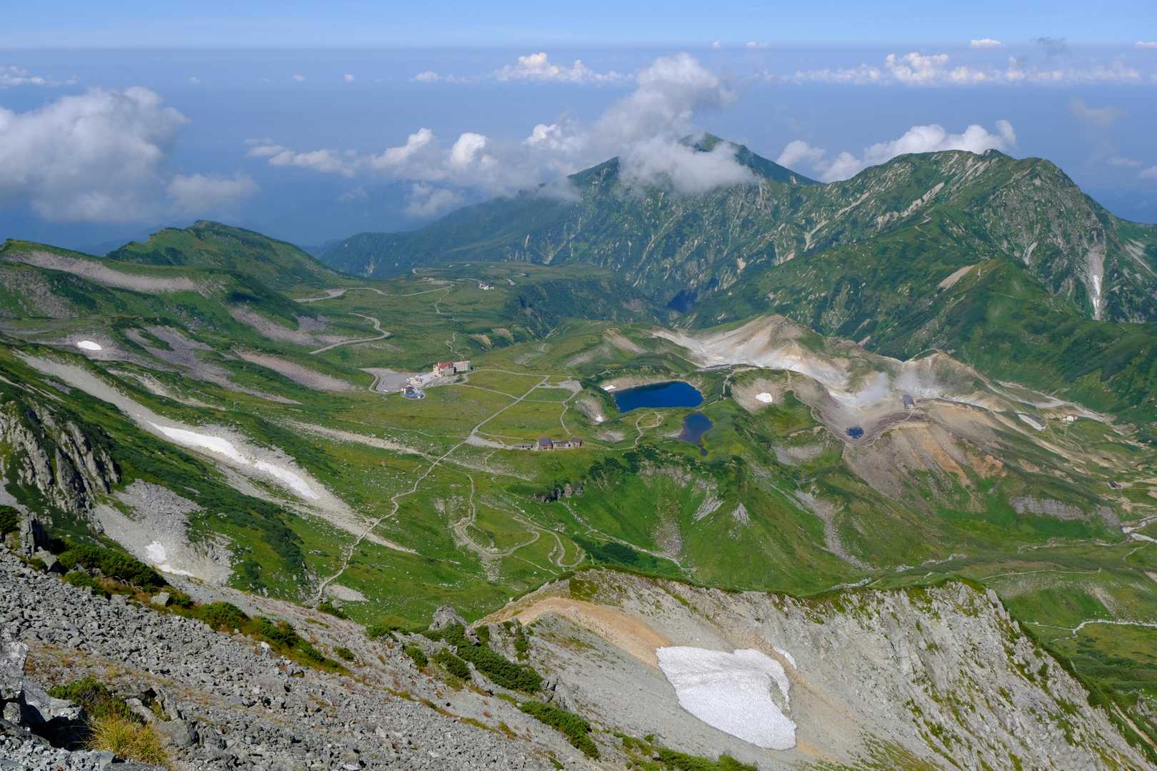 こちらは、『雄山』山頂から見下ろす『室堂平』周辺。いにしえの火山活動により形成された、平坦な溶岩台地と沢山の噴火口跡とのコントラストが非常に面白い。写真奥の山稜は、『立山連峰』の支稜である『大日連峰』。
