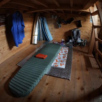 1階にてサーマレストのマットを膨らませる。掛け布団はエマージェンシーシートのみでよい。小屋に置かれている銀マットの何枚かが濡れていた。