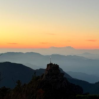 天狗岩を拡大。
朝焼けの山々のグラデーションと、凛とした天狗岩の宝剣。無意識に手を合わせてしまう自分がいる。


-----大嶽山那賀都神社HPより抜粋-----
御祭神は大山祇神・大雷神・高龗神の人皇十二代景行天皇の御代、日本武尊東夷御征定の砌、甲武信の国境を越えさせ給う時神助を蒙り、神恩奉謝の印として国司ヶ岳の天狗尾根（2436m）に佩剣を留め置き三神を斎き祀る（現・奥宮）。