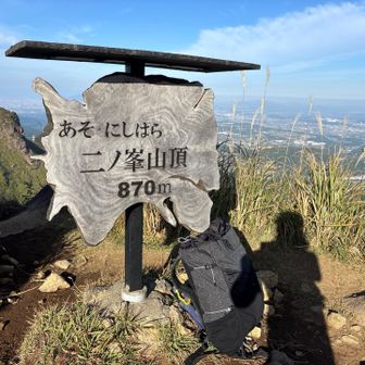 山頂標識の前ザックの横に朝日で映し出された影が怪しい