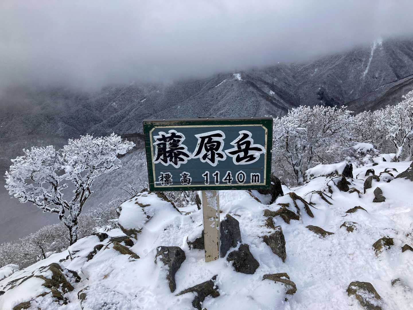 山頂に到着。幸い強風ではなかった。北から雲が絶え間なく流れてきて晴れ間は期待できなかった。体を冷やさないように長居せず下山😃