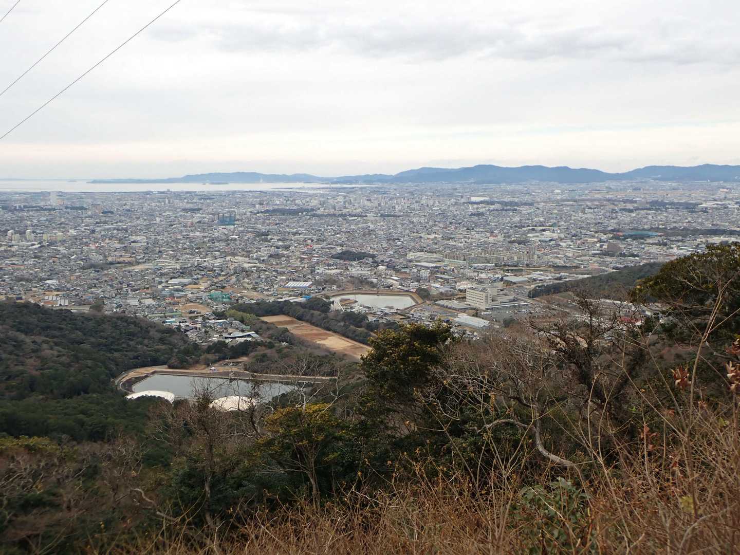 送電線の下が伐採されて見やすくなっている。豊橋市の市街がよく見える。さらに向こうは三河湾。