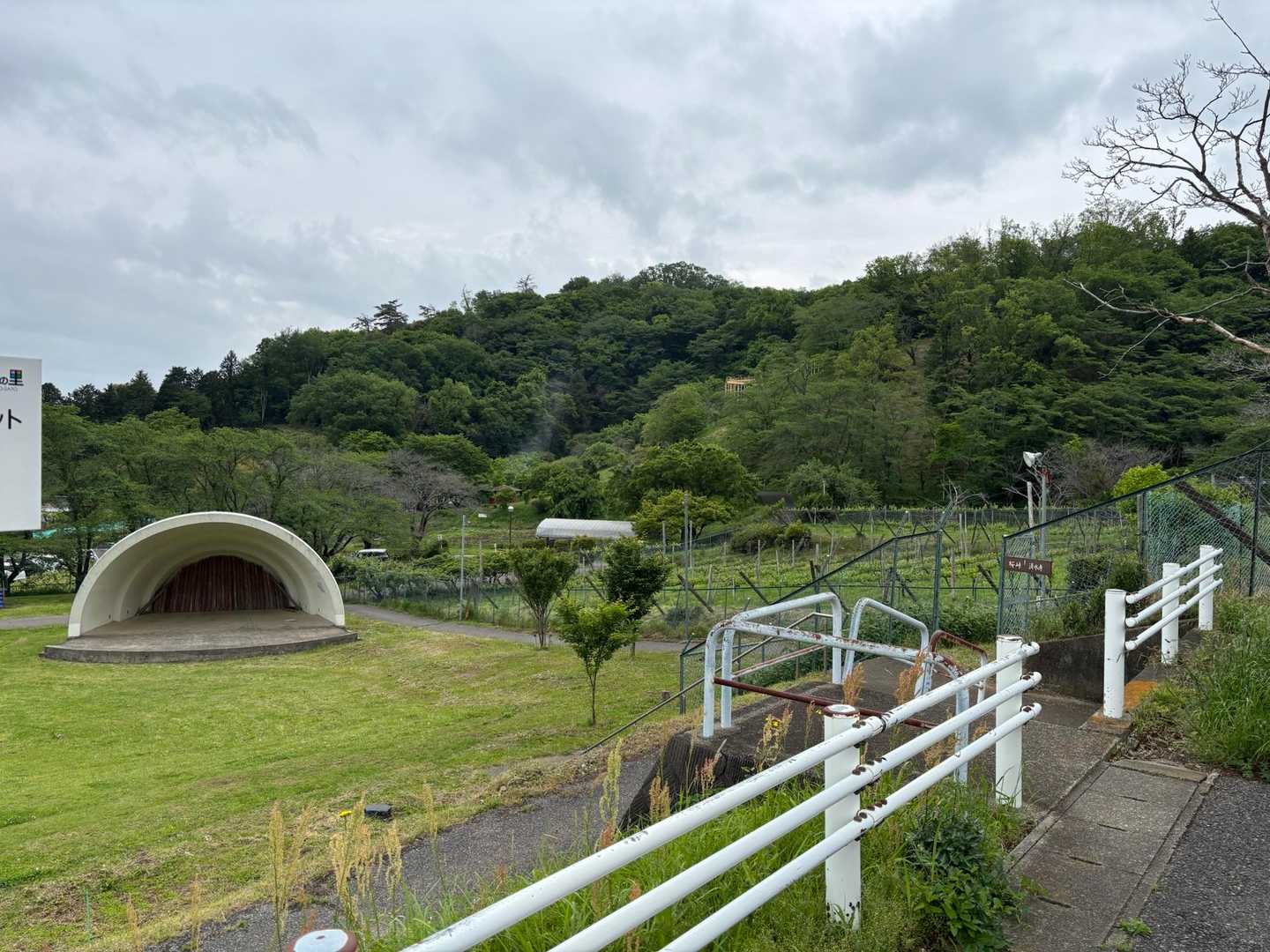 駐車場から屋外ステージの脇を通って片岡山に向かいました。写真中央の片岡山に至る道は、山の中腹に僅かに見える滑り台付近まで舗装されていました。