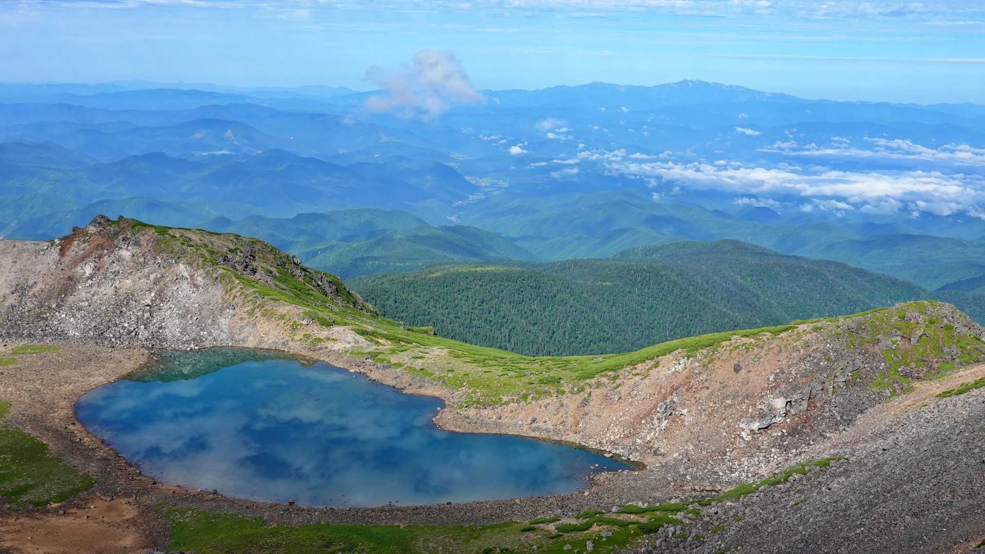 権現池の先には岐阜の町や山。そしてその奥に裾野を広げる白山
