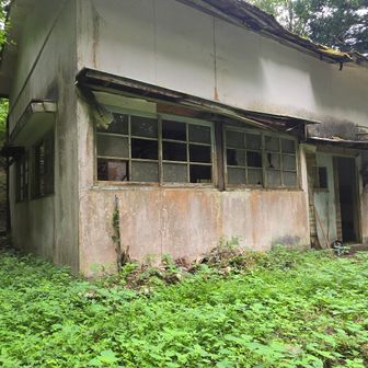 入口に登山靴とボトルが置かれてる　かつて牧場の施設であったらしい