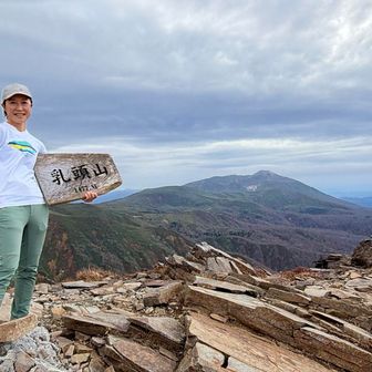 山頂には私以外にソロ男性。秋田駒ケ岳をバックにお願いして。看板、実はめちゃ重い。
