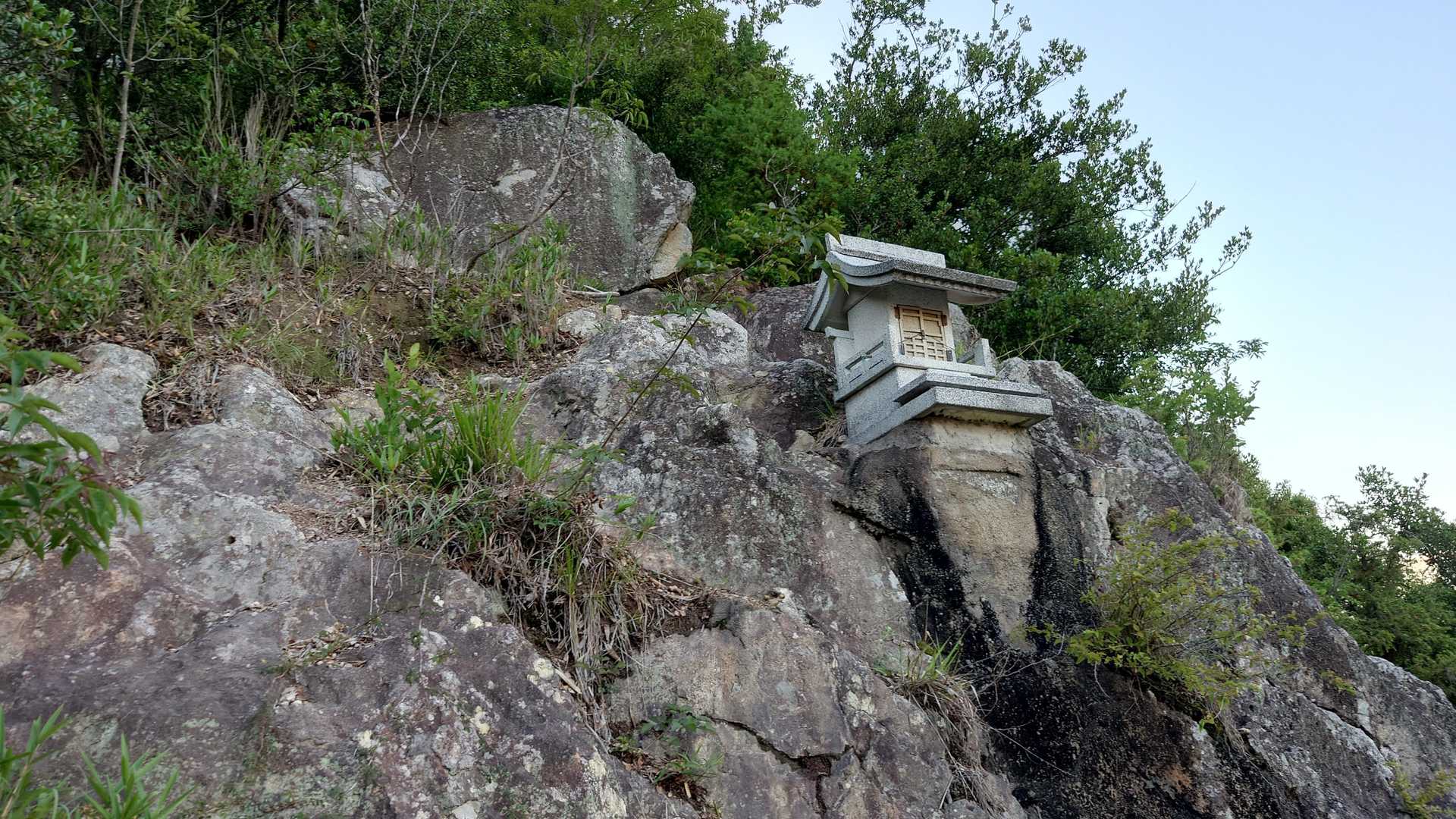 岩場から見守るお社。