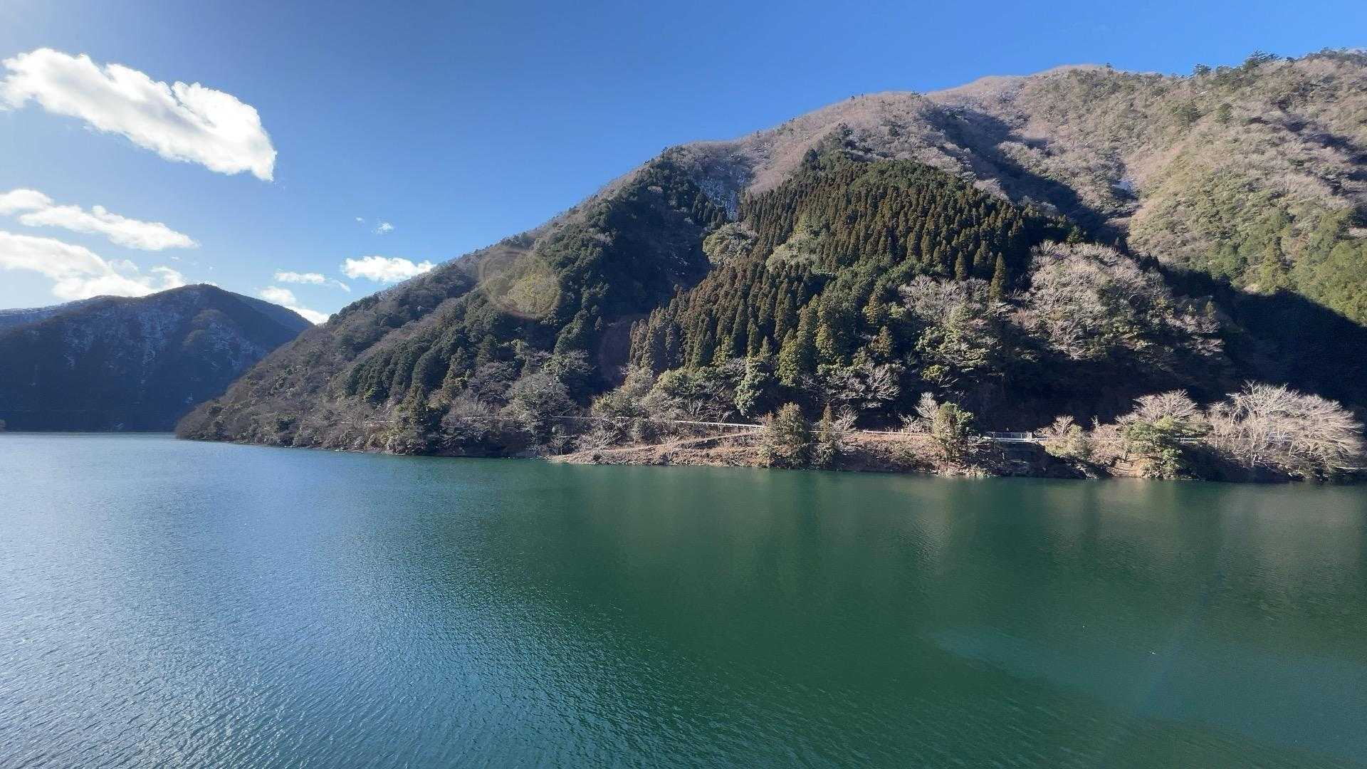 空の青と山の緑がリフレクトするエメラルドグリーンのダム湖がこの日の山行の終着点。