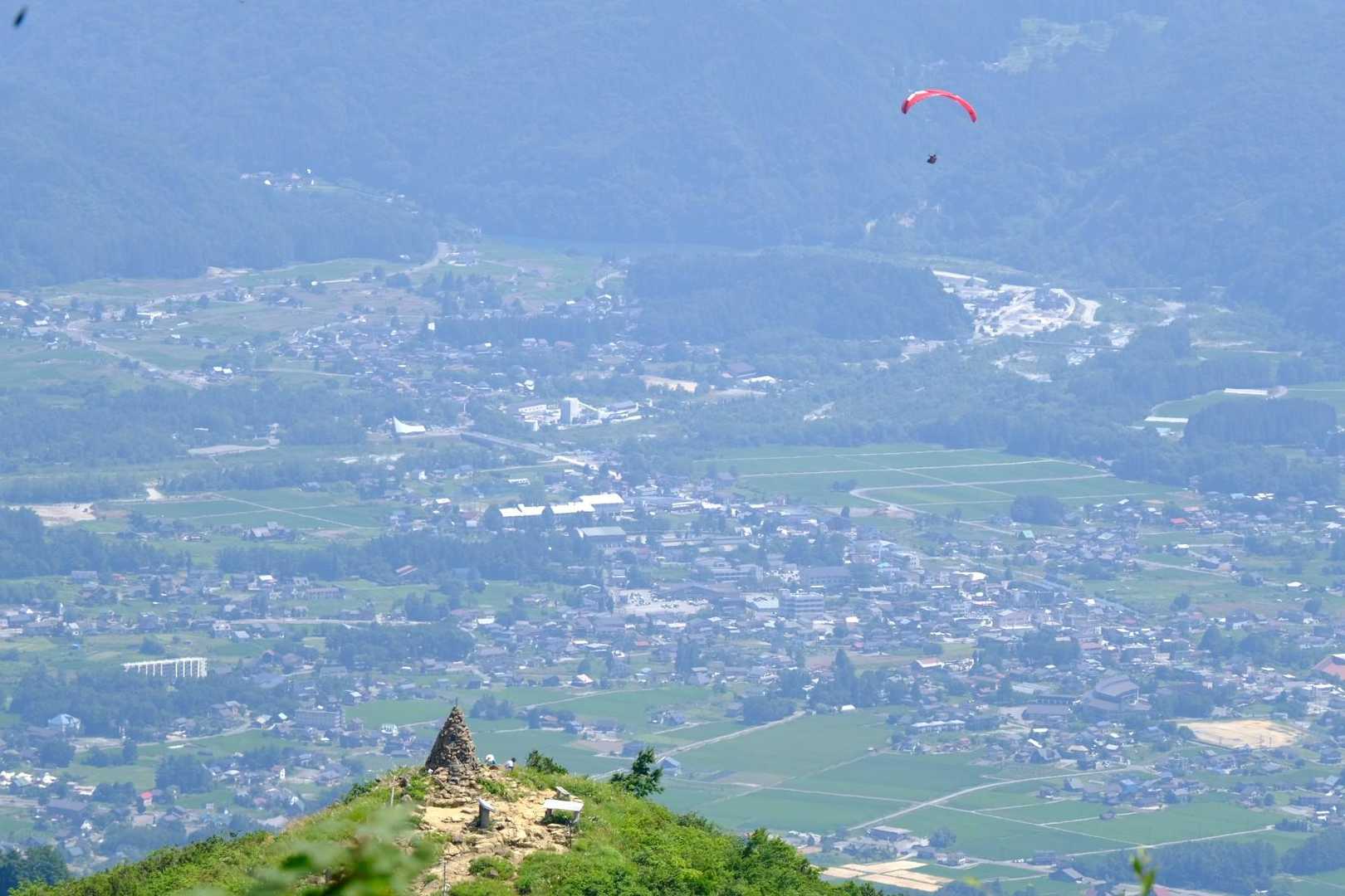 見返り坂から地蔵の頭とパラグライダーに白馬の街並み