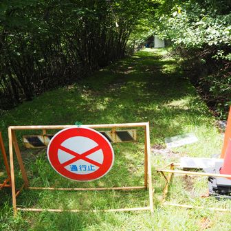 倒れているフェンスの近くに車両通行止めの表示