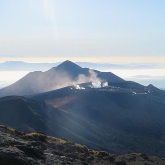 高千穂峰とその手前で噴煙を上げる新燃岳。