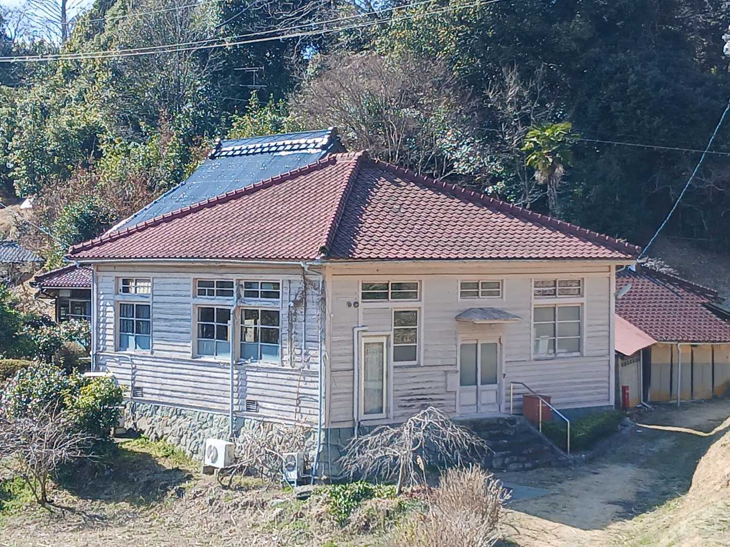 昔懐かしい建物ですね～⤴️⤴️

建物は、**「旧三国（みくに）郵便局」**です。

​​建築年: 1937年（昭和12年）に建てられた木造の建物です。

​外観: レトロな洋風建築の趣があり、寄棟造り（よせむねづくり）の下見板張り（横板を重ねて張る手法）の外壁が特徴です。
戦前に建てられた貴重な郵便局舎として、歴史的価値が認められています。

​歴史: もともとはこの地域の旧村名である「三国村」にちなんで命名されました。2006年まで集配業務を行い、その後無集配局となりましたが、2012年（平成24年）に廃止されるまで実際に使用されていました。

​場所: 八塔寺ふるさと村の景観の一部となっており、建物の前には昔ながらの丸型の赤いポスト（現在は撤去されているとの情報もあります）が置かれていたことでも知られています。

​現在は郵便局としての機能はありませんが、周囲の茅葺き民家が並ぶのどかな風景の中で、ノスタルジックな雰囲気を醸し出すスポットとして親しまれています。