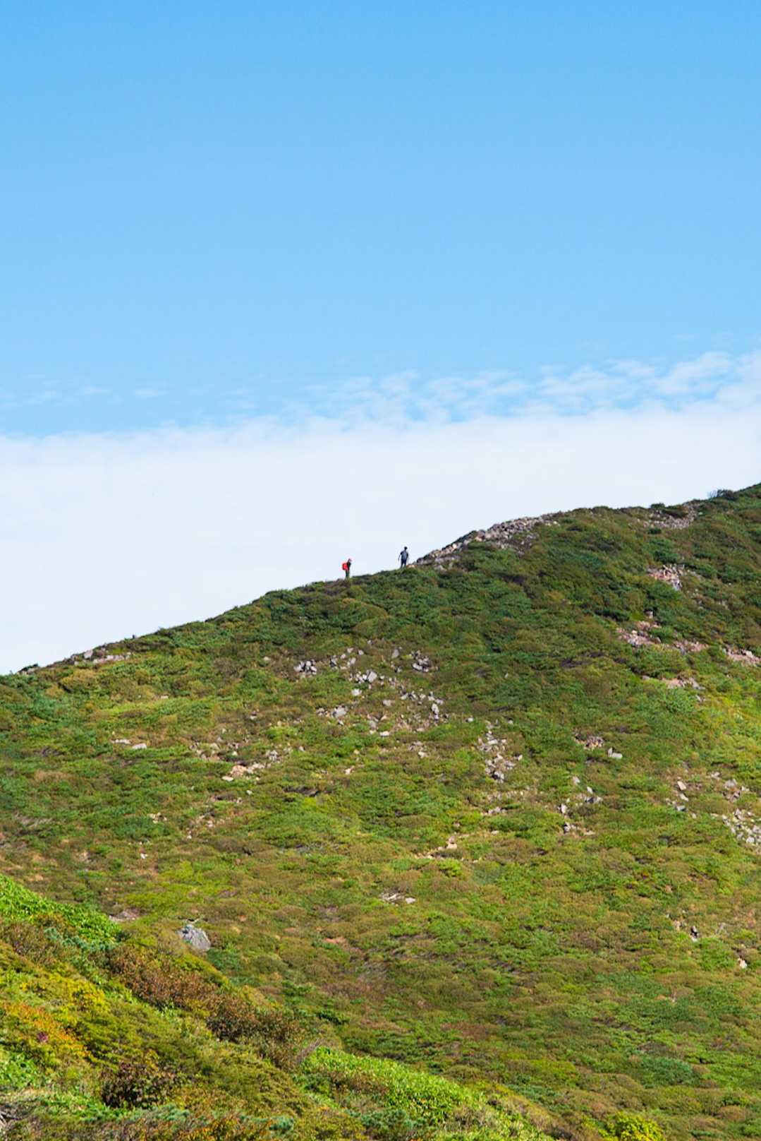 向かい側の1900m峰への稜線を歩く二人連れ