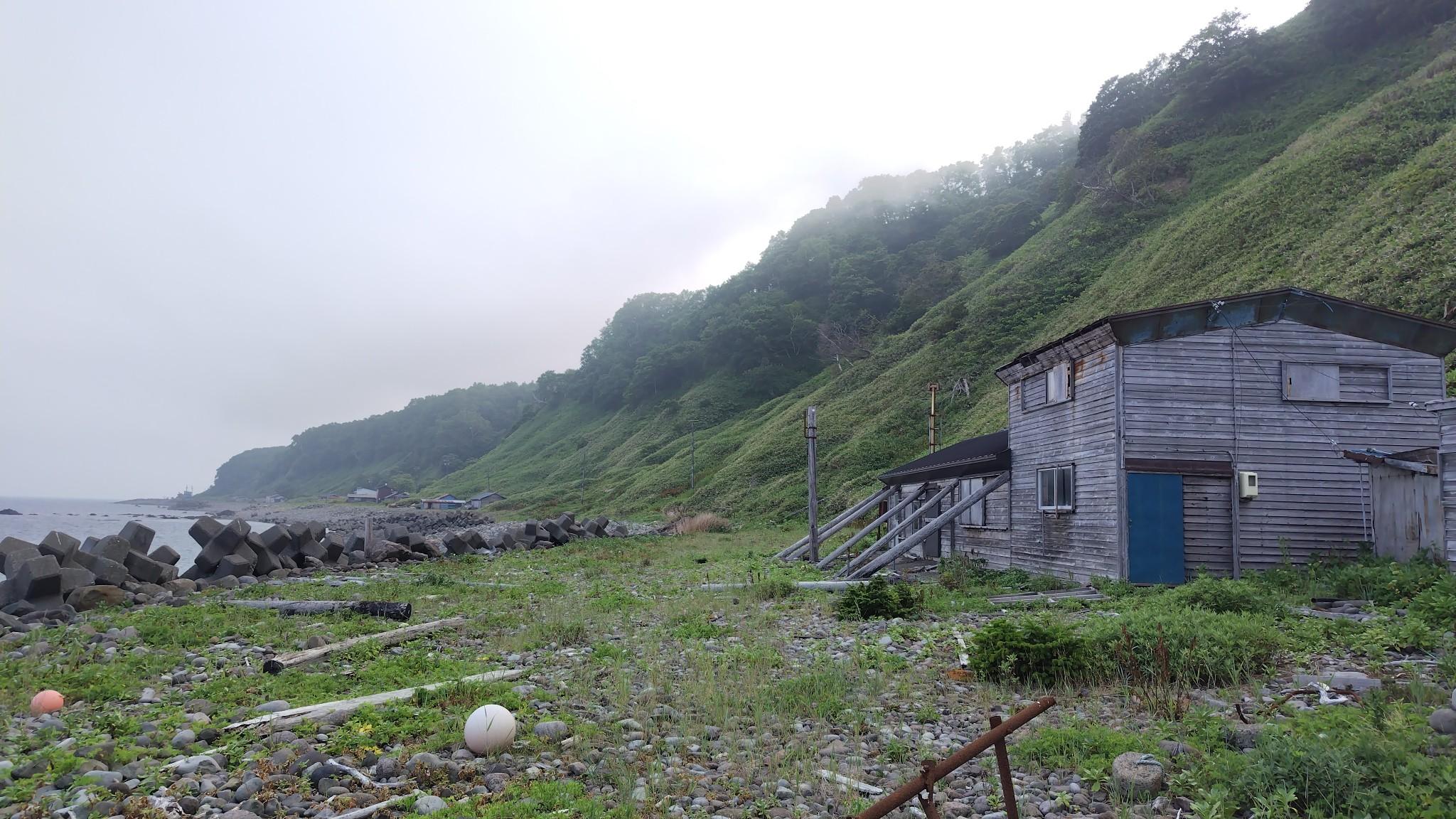 番屋のさらに奥の薄っすらと見える人工物の部分が相泊港。